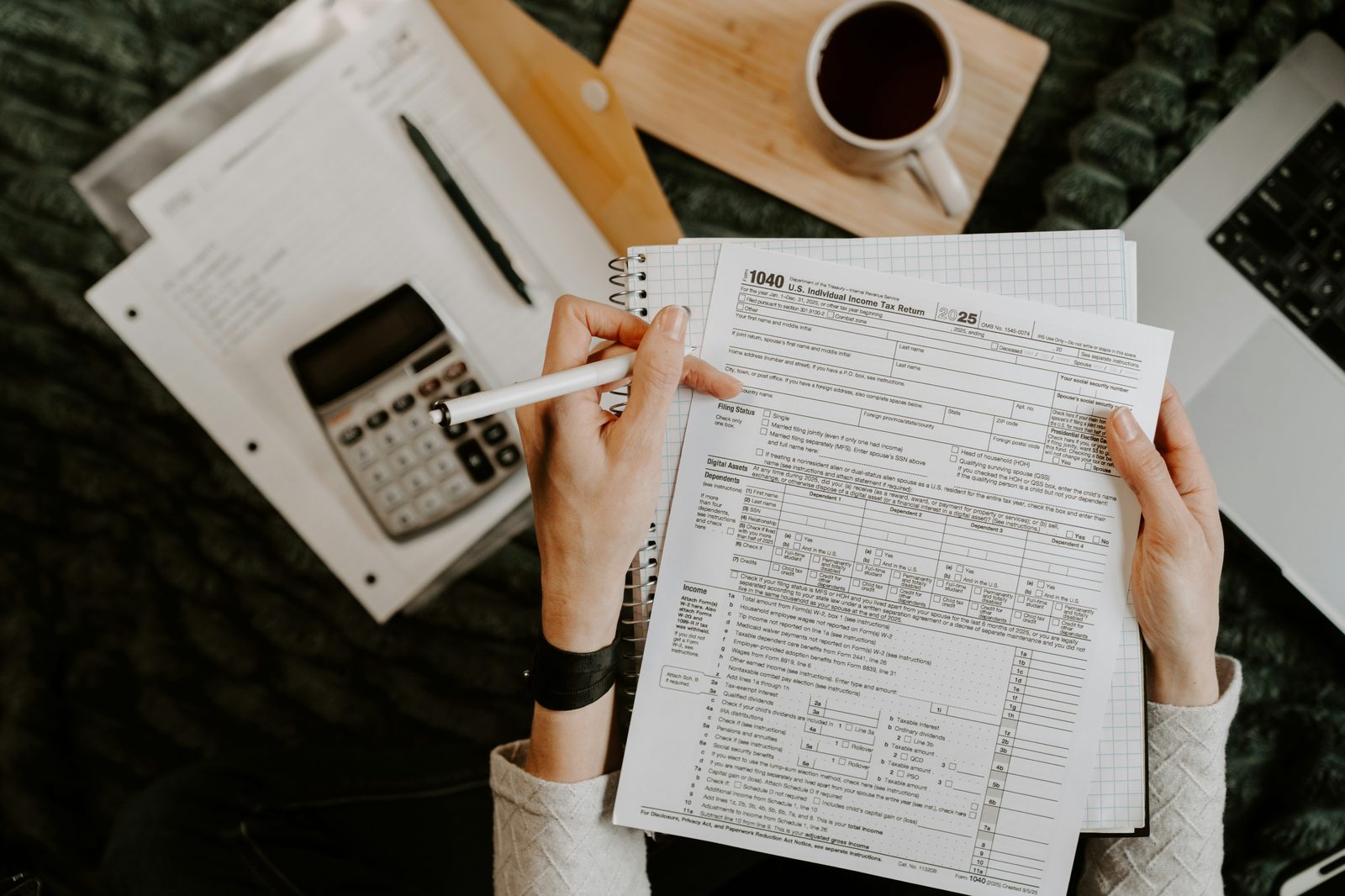 Person reviewing their monthly finances at a desk with a calculator and laptop