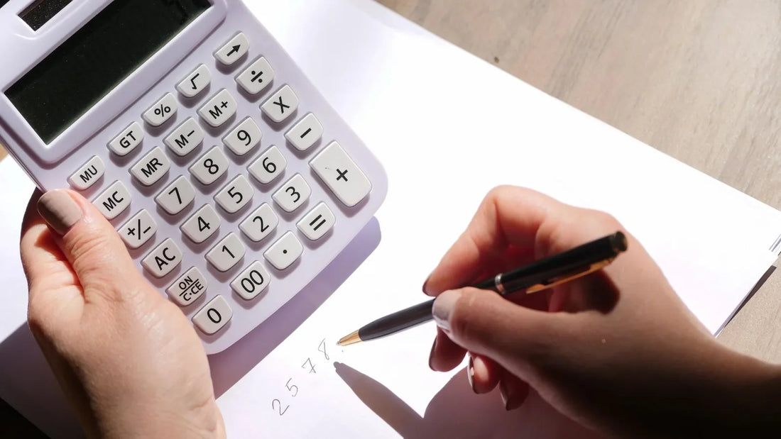 Hands using a calculator and writing numbers on a sheet of paper