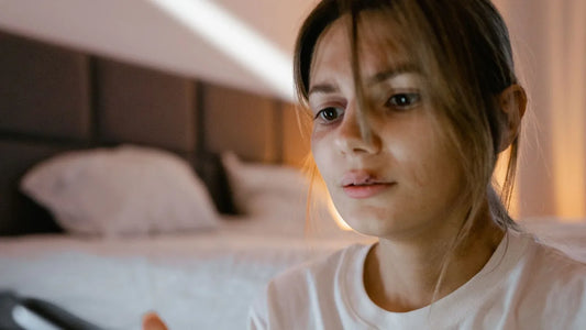 Worried young woman looking down at something in her hands in a dim bedroom
