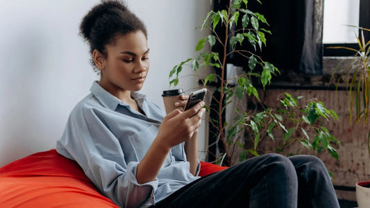 Woman relaxing on a beanbag with her phone and a coffee cup