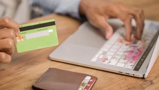 Person holding a bank card while typing on a laptop