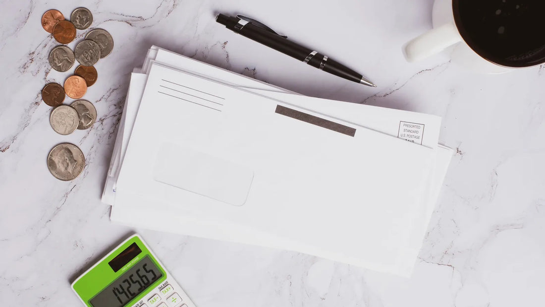 Envelopes, coins, a calculator and a pen on a marble table