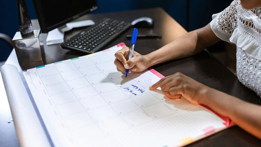 Wall calendar marked with bill due dates and reminder notes for monthly bill payments