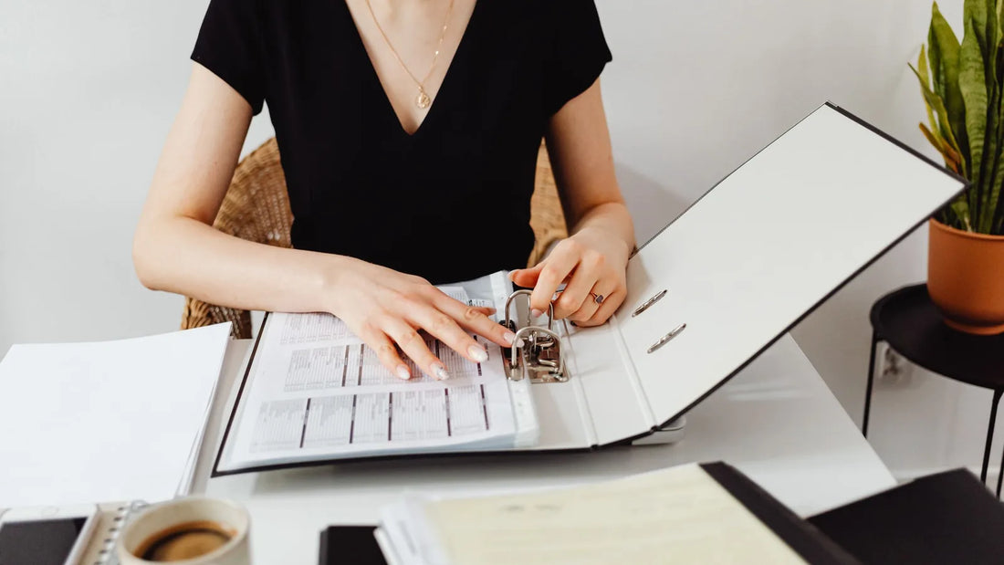 Woman sorting papers in a ring binder at her desk