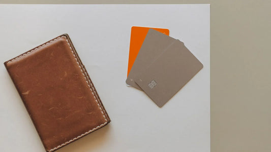 Three payment cards laid next to a brown leather wallet on a white surface