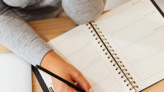 Overhead view of a person writing in a planner while setting financial goals