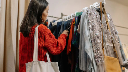 Woman browsing a clothing rack in a thrift store as part of a frugal living habit