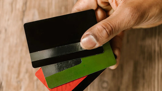 Hand holding three credit cards, showing the plain backs