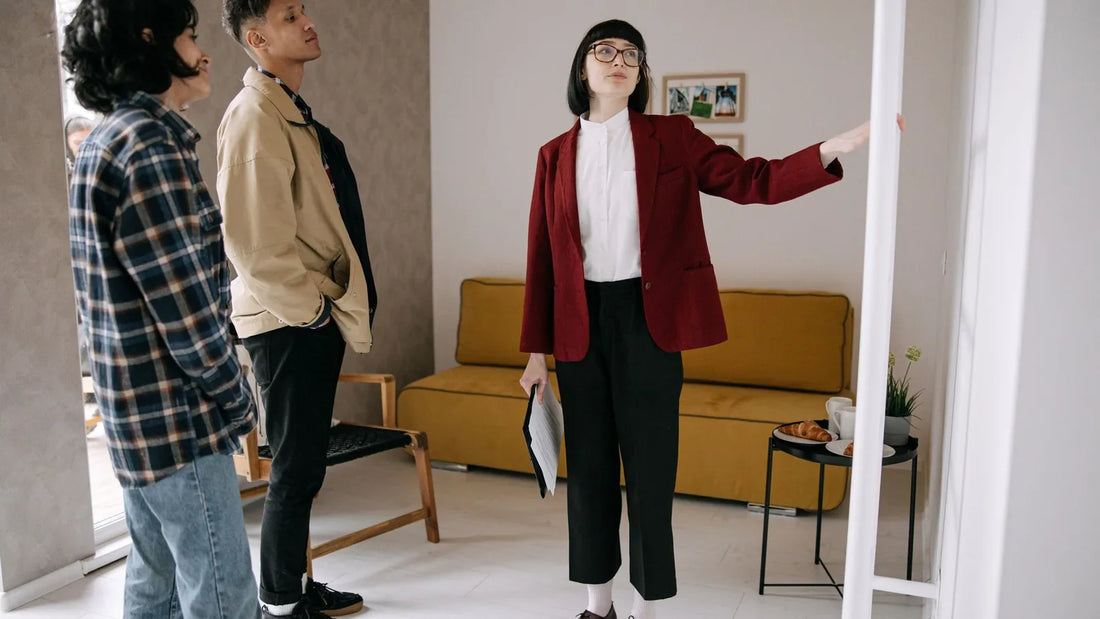 Two renters touring an apartment's living room while a leasing agent points out features