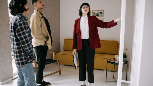 Two renters touring an apartment's living room while a leasing agent points out features