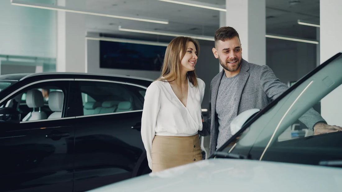 Couple browsing new cars in a dealership showroom, considering an upgrade after a raise