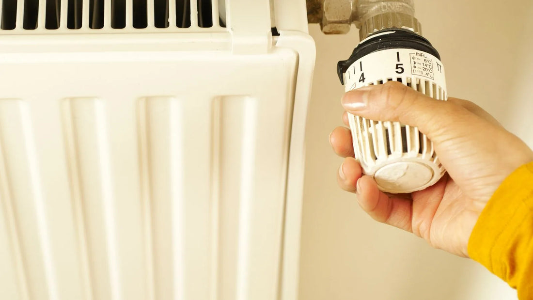 Close-up of a hand adjusting a radiator thermostat valve