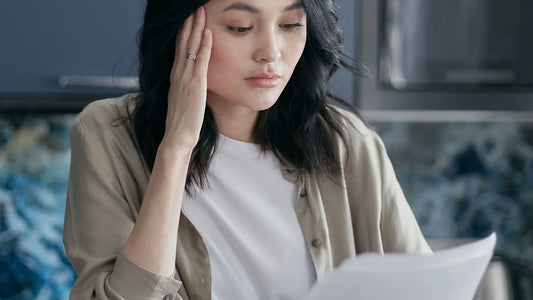 Woman with her hand on her forehead reading a bill at home