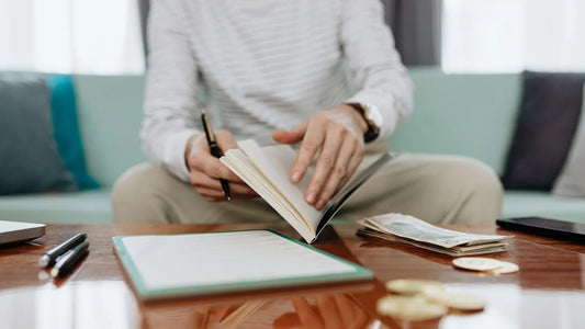 Person comparing planned budget numbers against actual spending in a notebook during a monthly review