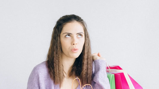 Young woman holding colorful shopping bags with a thoughtful expression