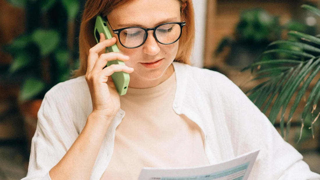 Woman in glasses talking on the phone while reading a document