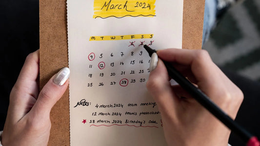 Close-up of hands marking off days on a calendar with a pen