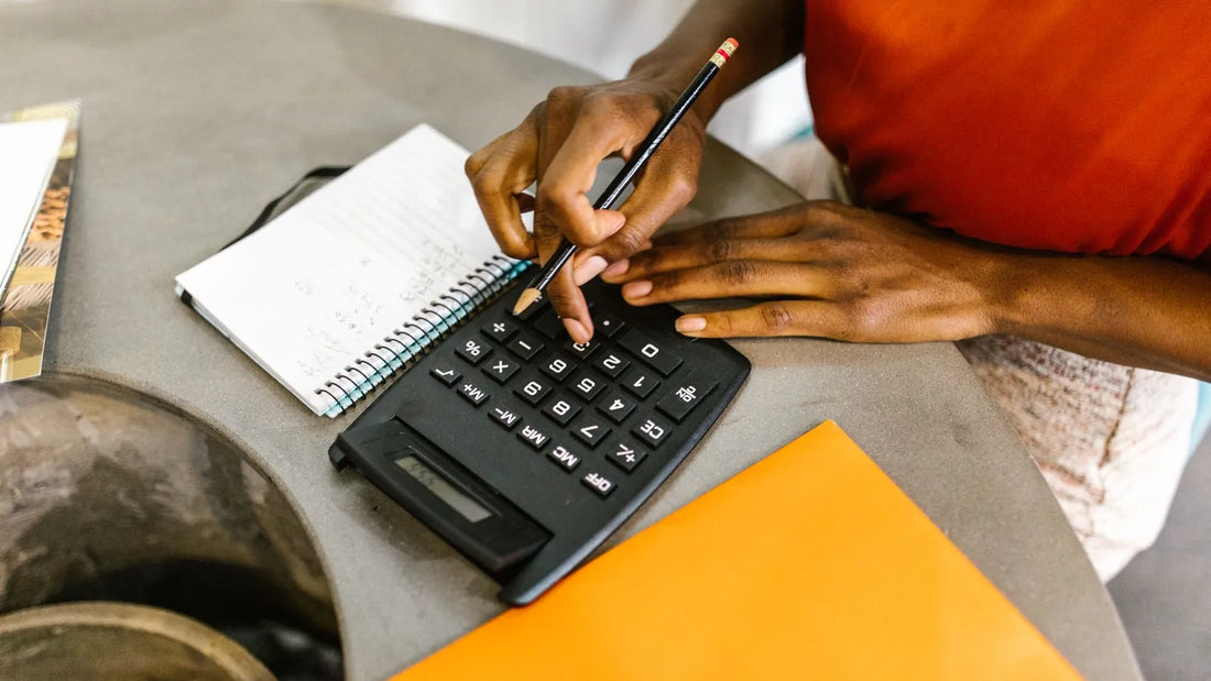 Hands using a calculator and writing in a notebook to plan debt payments
