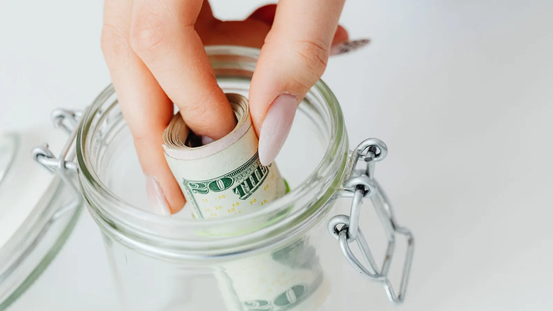 Hand placing rolled dollar bills into a glass jar