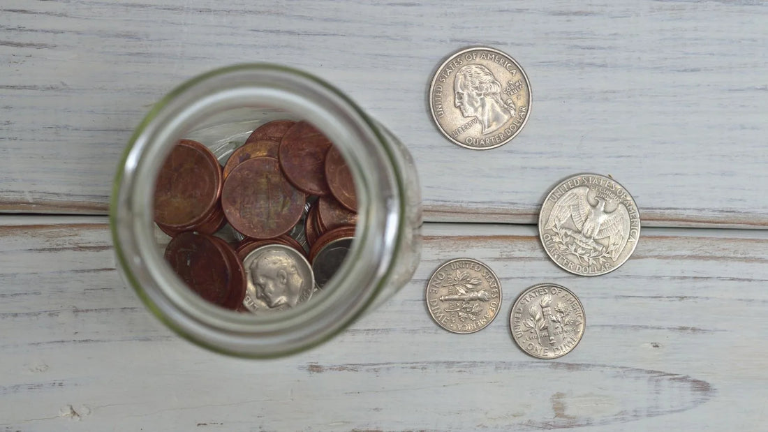 Overhead view of a jar filled with coins on a wooden table, representing a savings goal
