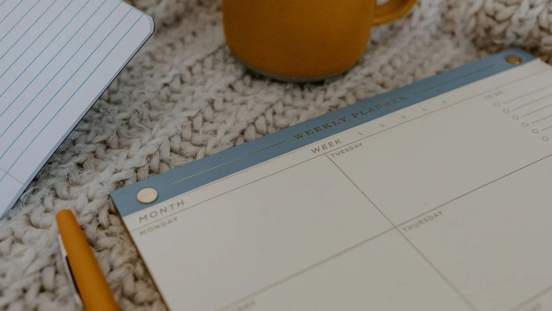 Blank planner page with a pen and a mug of coffee on a knitted blanket