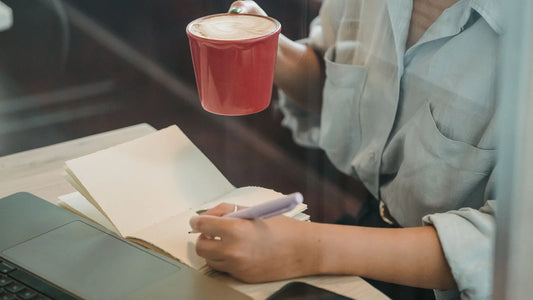 Person relaxed at a café table with a small notebook, planning a guilt-free spending category instead of a restrictive budget