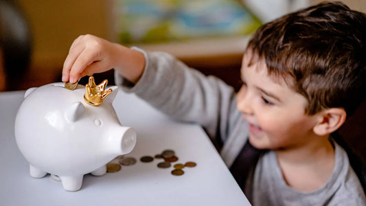 Young boy smiling while putting coins into a piggy bank