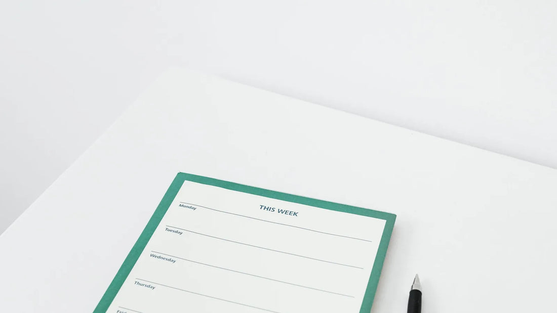 Minimal weekly planner page with a pen on a white desk