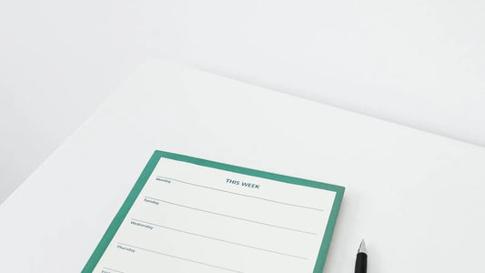 Minimal weekly planner page with a pen on a white desk
