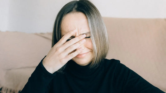 Frustrated woman pressing a hand to her forehead while sitting on a sofa